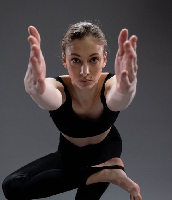 Serene woman practicing yoga in a dark aesthetic studio.